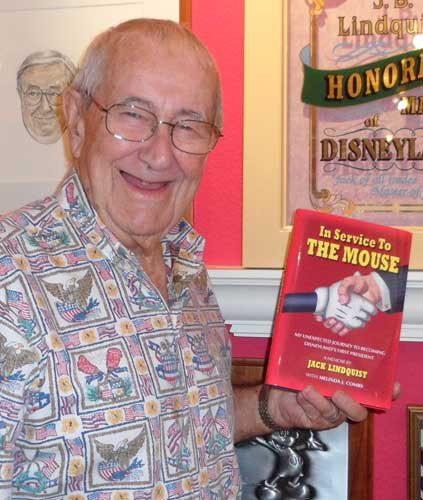 Jack Lindquist holds a copy of his book, "In Service To The Mouse" in his office